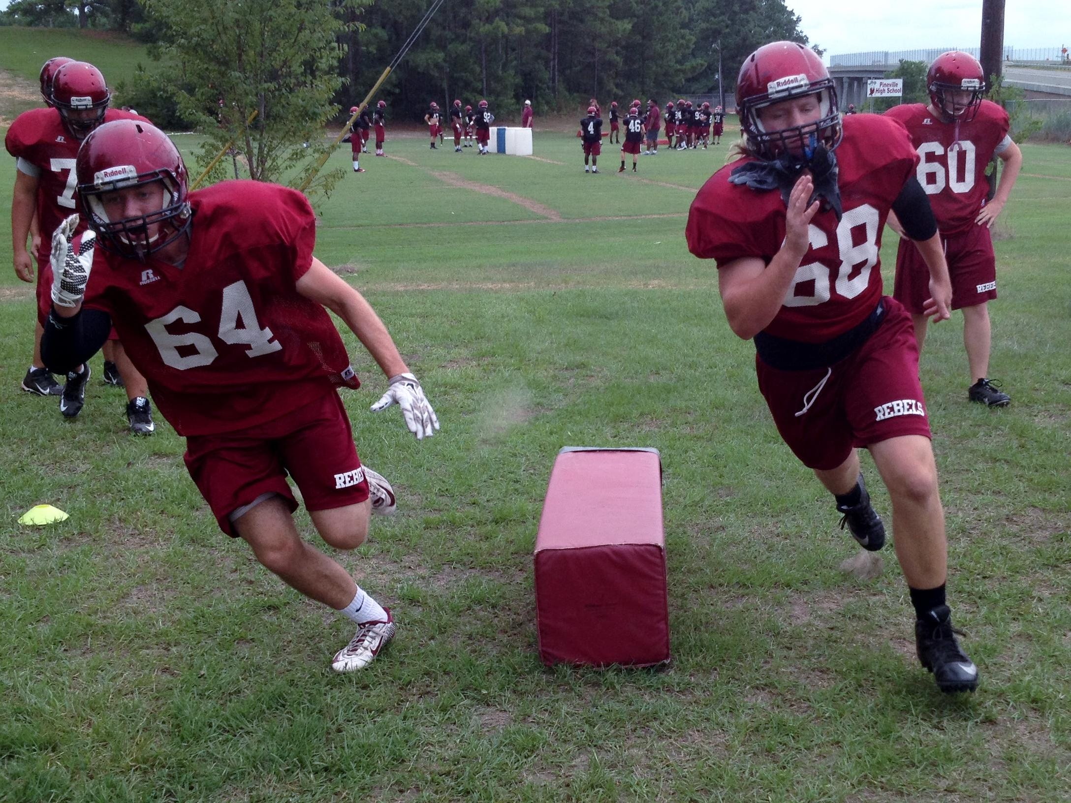Pineville senior right tackle Harrison Nugent (64) and right guard Dakota Cross (68) run through a drill during practice Tuesday. The undersized Nugent is one of the top academic and most involved students at Pineville High School.