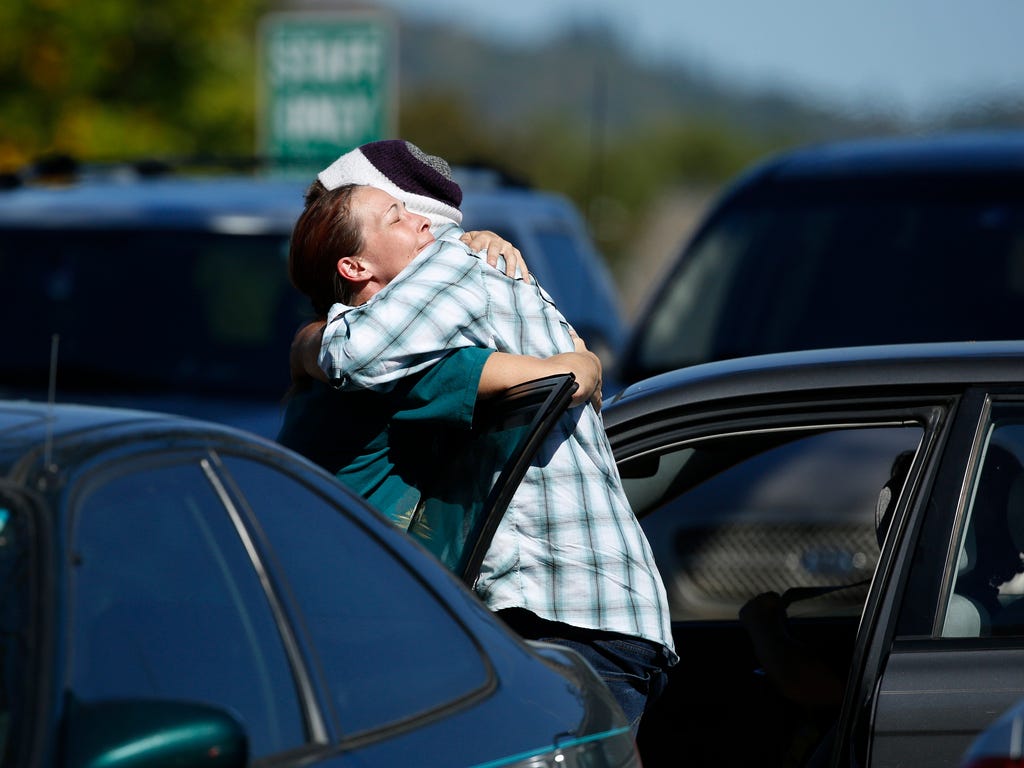 Student Mathew Downing, right, is hugged by a woman as they return to Umpqua Community College in Roseburg, Ore.