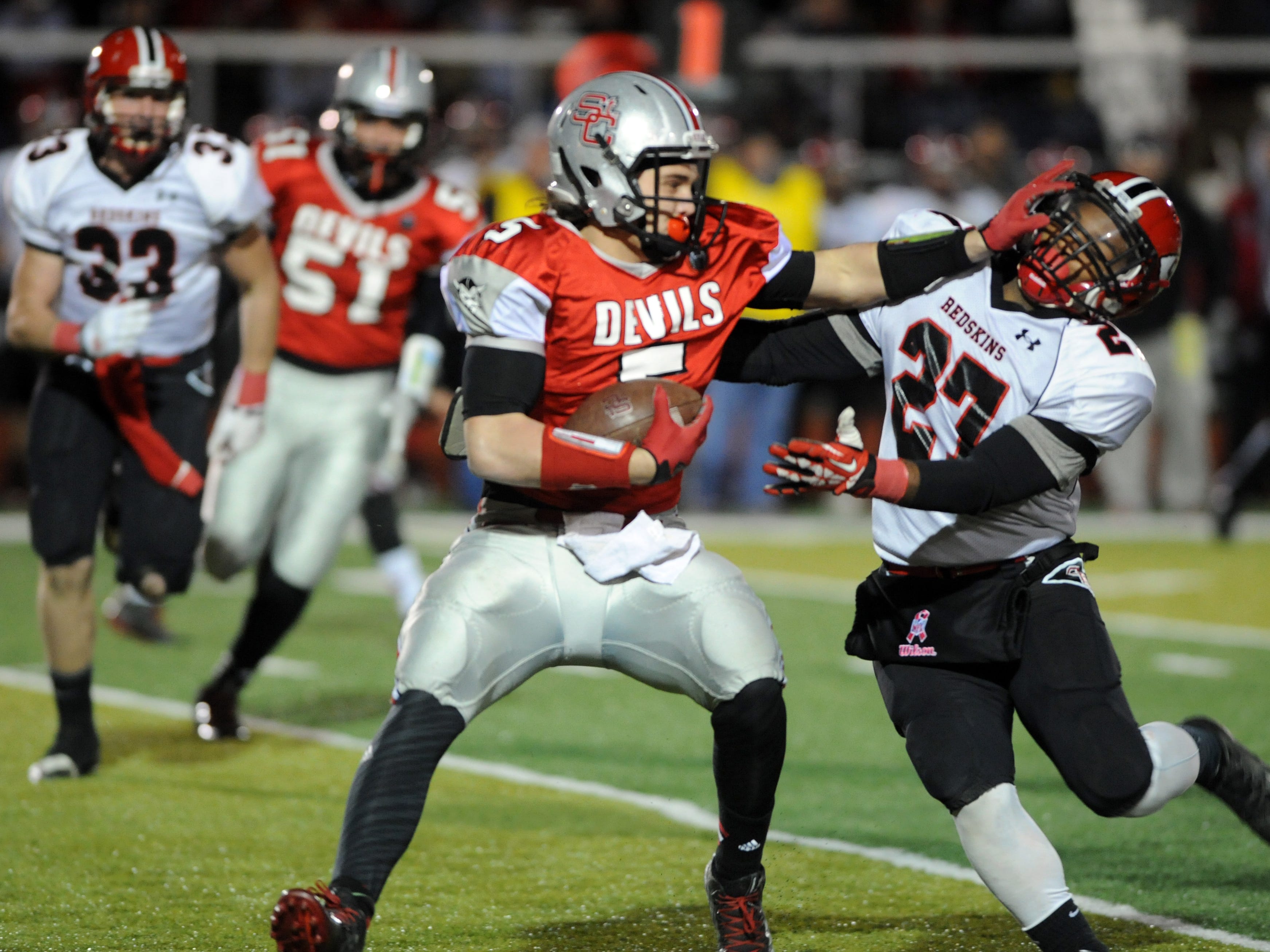 St. Clairsville's Brendan Ferns stiff-arms Coshocton's Dom Johns during Saturday’s playoff game at St. Clairsville High School. The Red Devils defeated the Redskins, 28-7.