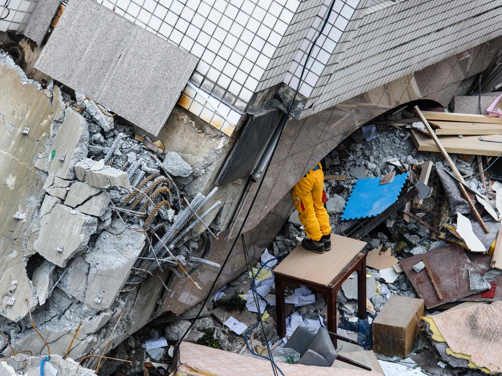 A rescue worker clears debris to make way for the recovery of the dead bodies from the Yun Tsui building, which is leaning at a precarious angle, in the Taiwanese city of Hualien after the city was hit by a 6.4 magnitude quake late on Feb. 6.