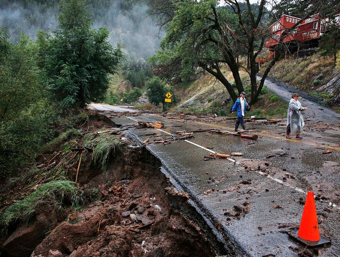 Patrick Tinsley, left, and his sister, Mary Kerns, walk along a closed road from their mountain community of Magnolia after a massive flood on Sept. 13 in Boulder Canyon, Colo.
