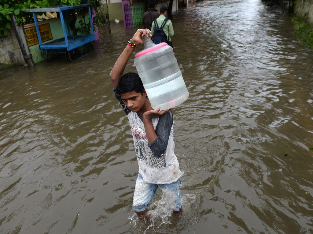 A youth carries a container of drinking water on his shoulders at a residential area flooded after heavy monsoon rains in Chennai, India.