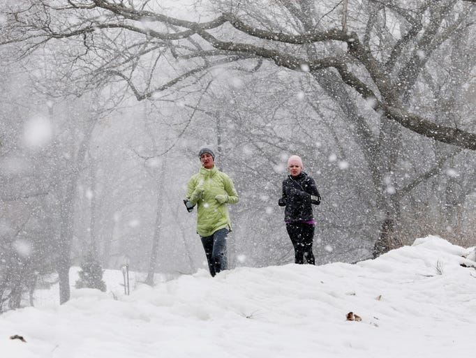 Snow falls as Joggers run in New York's Central Park.
