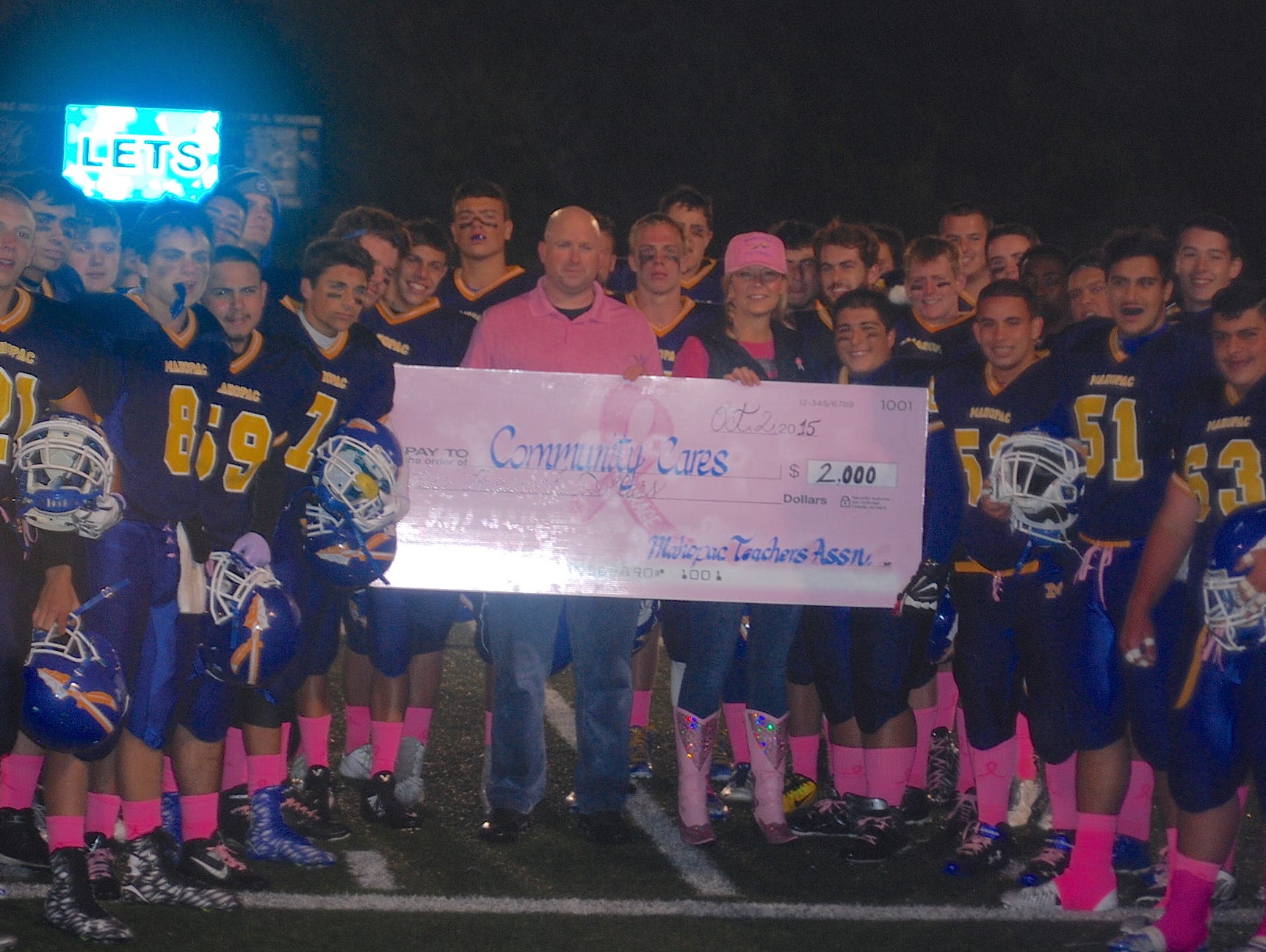 The Mahopac football team poses with a check that the school donated to Community Cares, a local non-profit, after its second annual "Pink Game" on Oct. 2, 2015.