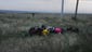 Luggage from the airliner sit in a field.