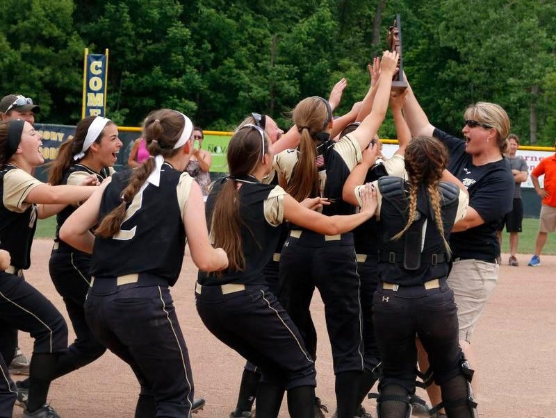 Holt players rush to coach Kim Reichard, right, and their district championship trophy after defeating Jackson 16-0, Saturday, June 4, 2016, at Grand Ledge High School.