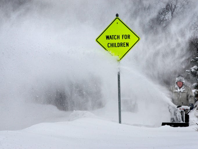 Snow blowing from trees swirls behind George Henzel of Winchester, Va., as he clears sidewalks for neighbors Feb. 13.