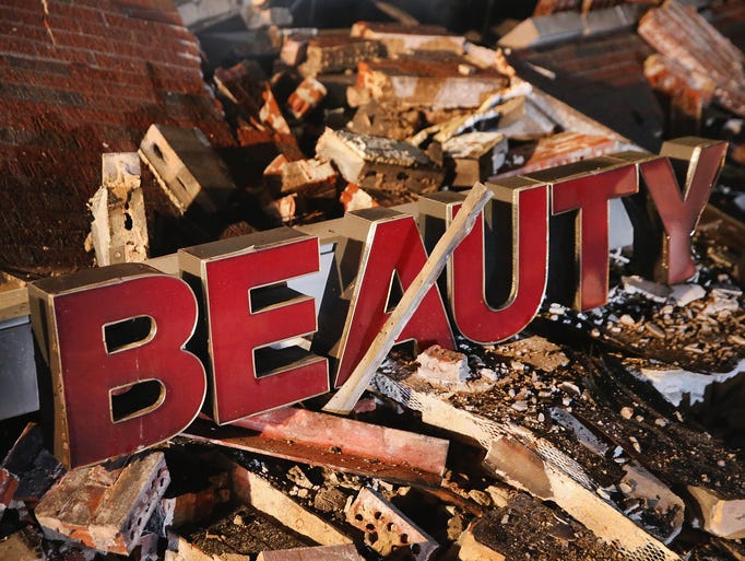 A sign rests in the rubble of a strip mall that was