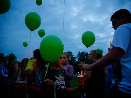 Scott Ross lights his daughter Chloe, 8, during a vigil