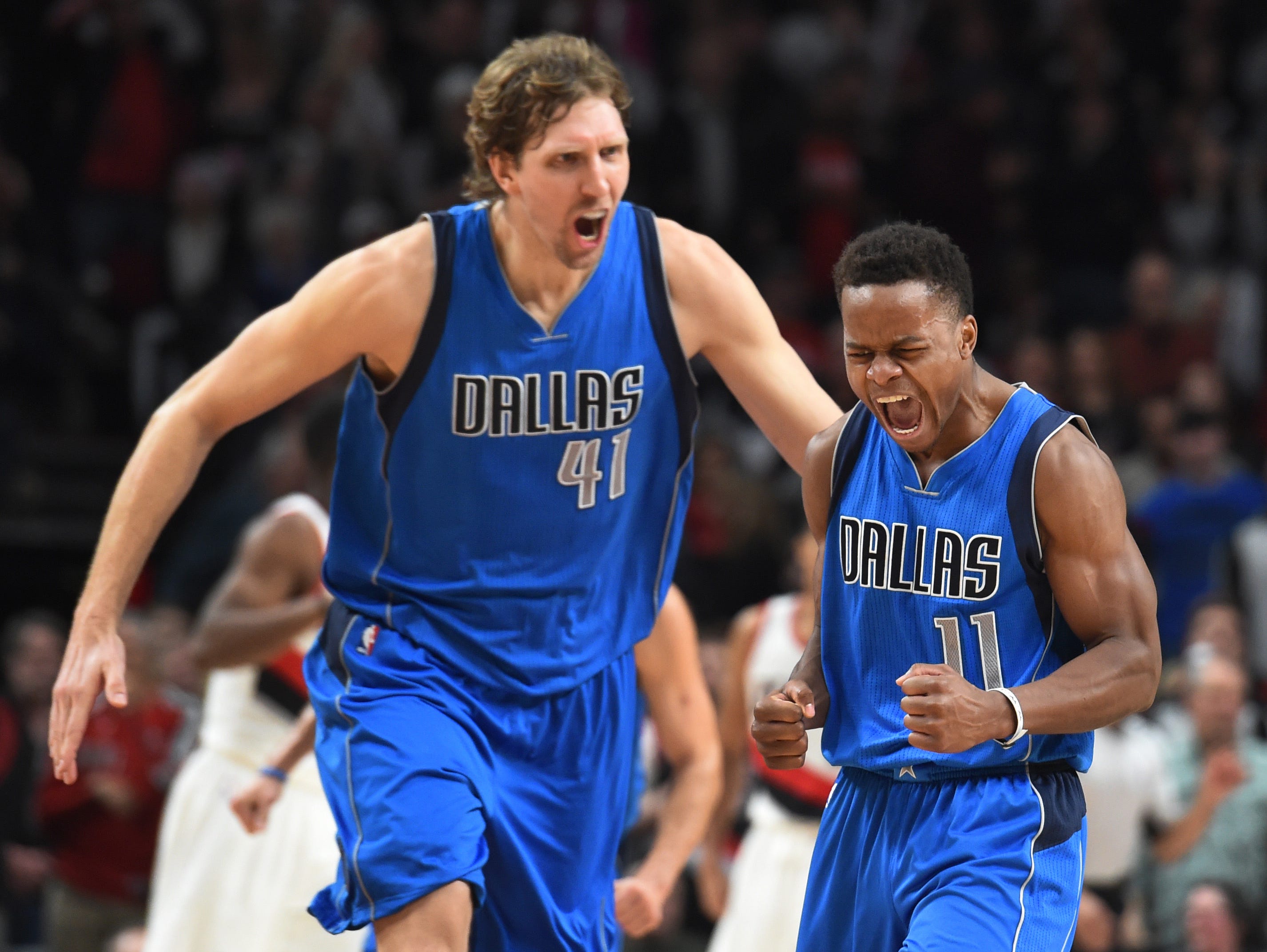 Dallas Mavericks guard Yogi Ferrell celebrates with forward Dirk Nowitzki after hitting a shot late in the fourth quarter of the game against the Portland Trail Blazers at the Moda Center. Dallas won the game 108-104.