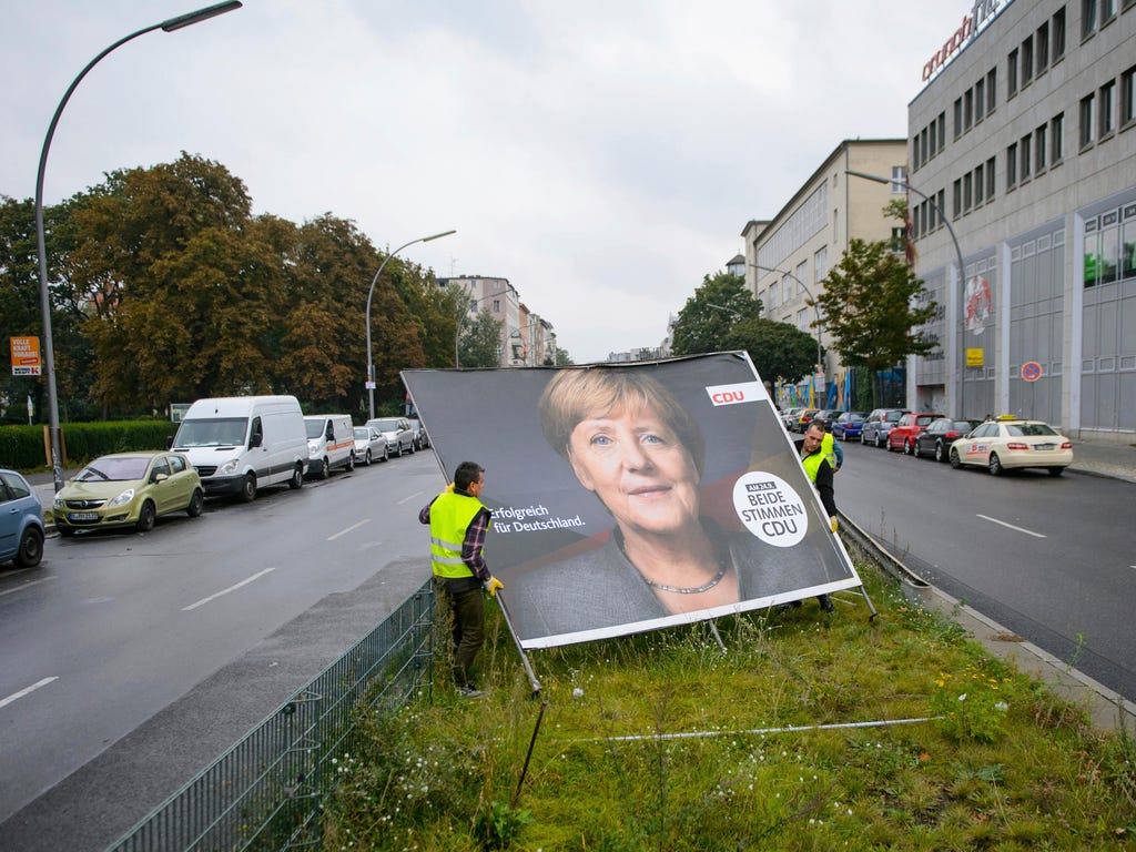 Workers remove an election poster of the Christian Democrats  with a photo of German chancellor Angela Merkel  in Berlin, Sept. 25, 2017 after Sunday's parliament elections. German Chancellor Angela Merkel was embarking Monday on a complicated quest 