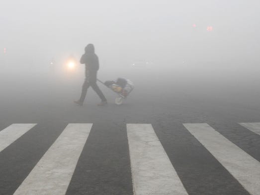 A pedestrian crosses a smog-shrouded street in Lianyungang,