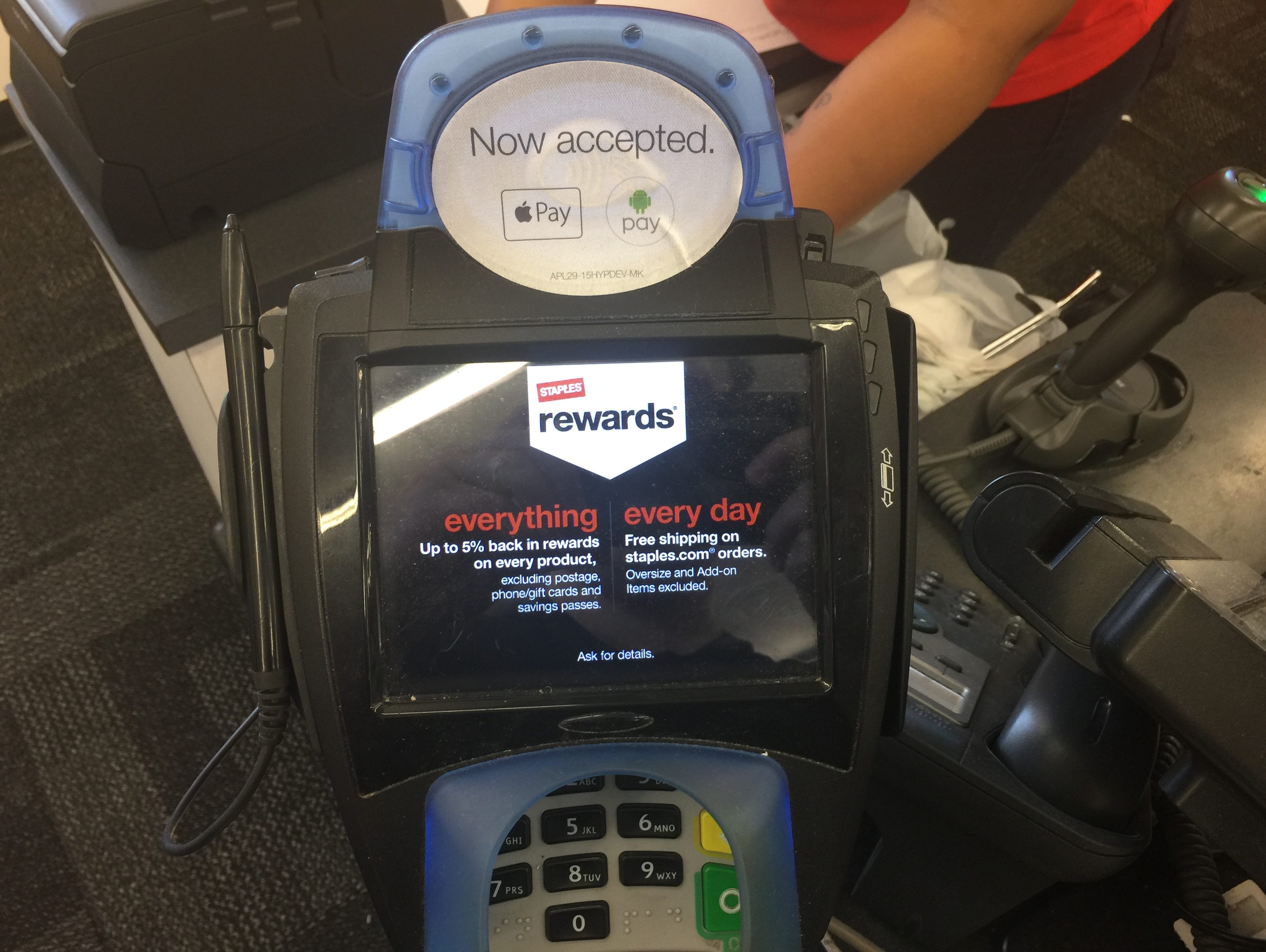 A terminal at Staples featuring both an Android Pay sticker and an Apple Pay sticker.