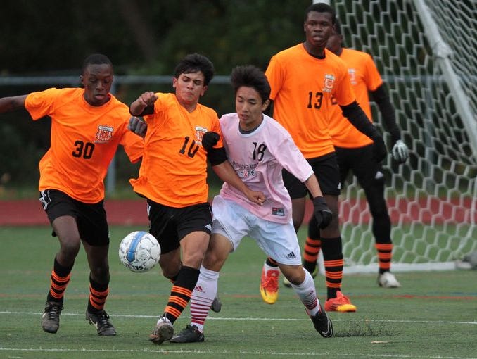 Spring Valley's Shebnaldy Dossous, left, and Jesus Vasquez battle for the ball against Rye's Takizawa Shota in a boys soccer Class A outbracket game in Rye Oct. 23, 2014. Rye won 3-0.
