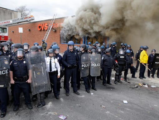 Police stand in front of a burning store in Baltimore