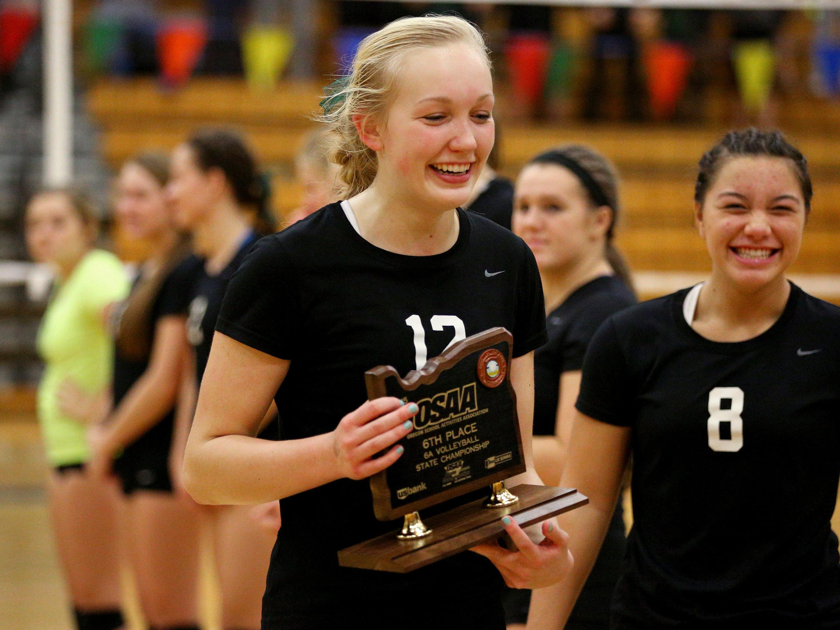 West Salem outside hitter Paige Whipple (12) carries the sixth place trophy back to her team after losing 3-2 against Sunset during the fourth place gameof the 6A state volleyball playoffs, Saturday, November 7, 2015, at Liberty High School in Hillsboro, Ore.
