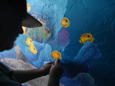 Local artist, Alan Mishagi touches up a mural on the