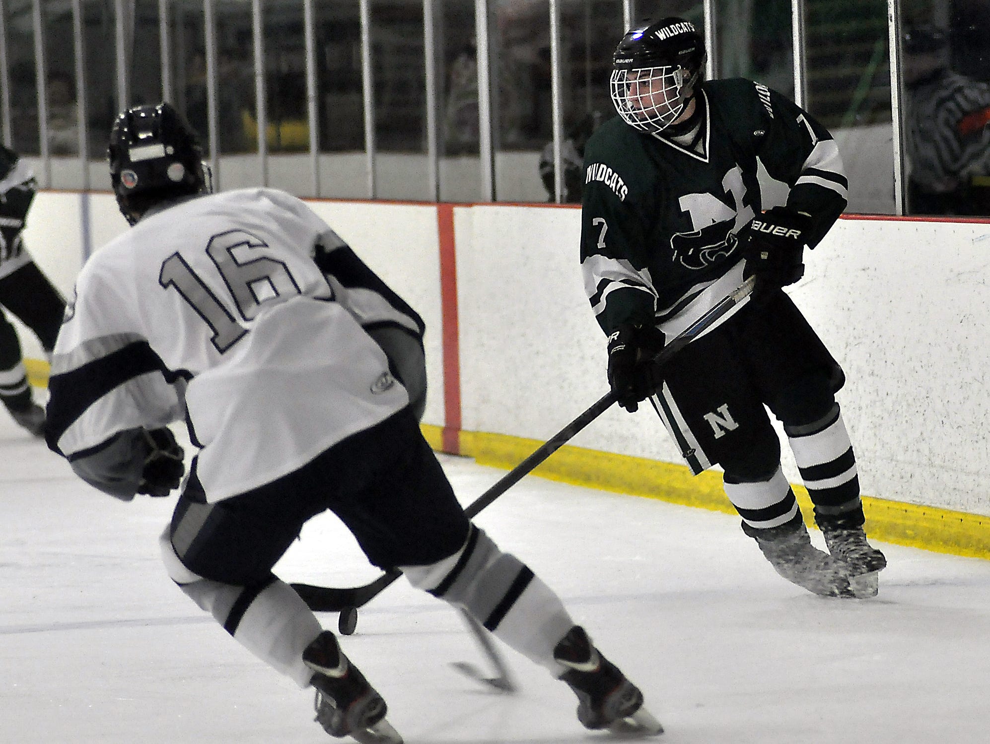 Novi's Alec Wells (7) moves the puck up up the ice on South Lyon Unified's Spencer Stanley (16).
