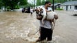 Andrew Hudson carries his dog Sugar after being rescued