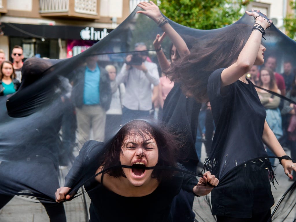 Women perform under black fabric during a street performance in Pristina against sexual harassments in Kosovo.