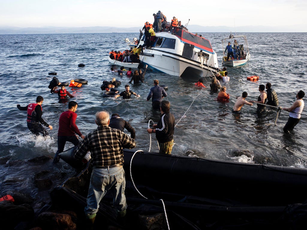 Volunteers and local residents help refugees and migrants disembark from a small vessel after their arrival in Skala Sykaminias on the northeastern Greek island of Lesbos. Greek authorities say a number of people have died near other islands after tw