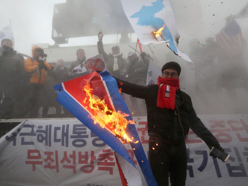 A protester burns a North Korean flag during a rally against North Korea's participation in the 2018 Pyeongchang Winter Olympics in Seoul on Feb. 11, 2018. A rare invitation to Pyongyang for South Korean President Moon Jae-in marked Day 2 of the Nort