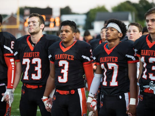 Hanover football players hold hands during the national