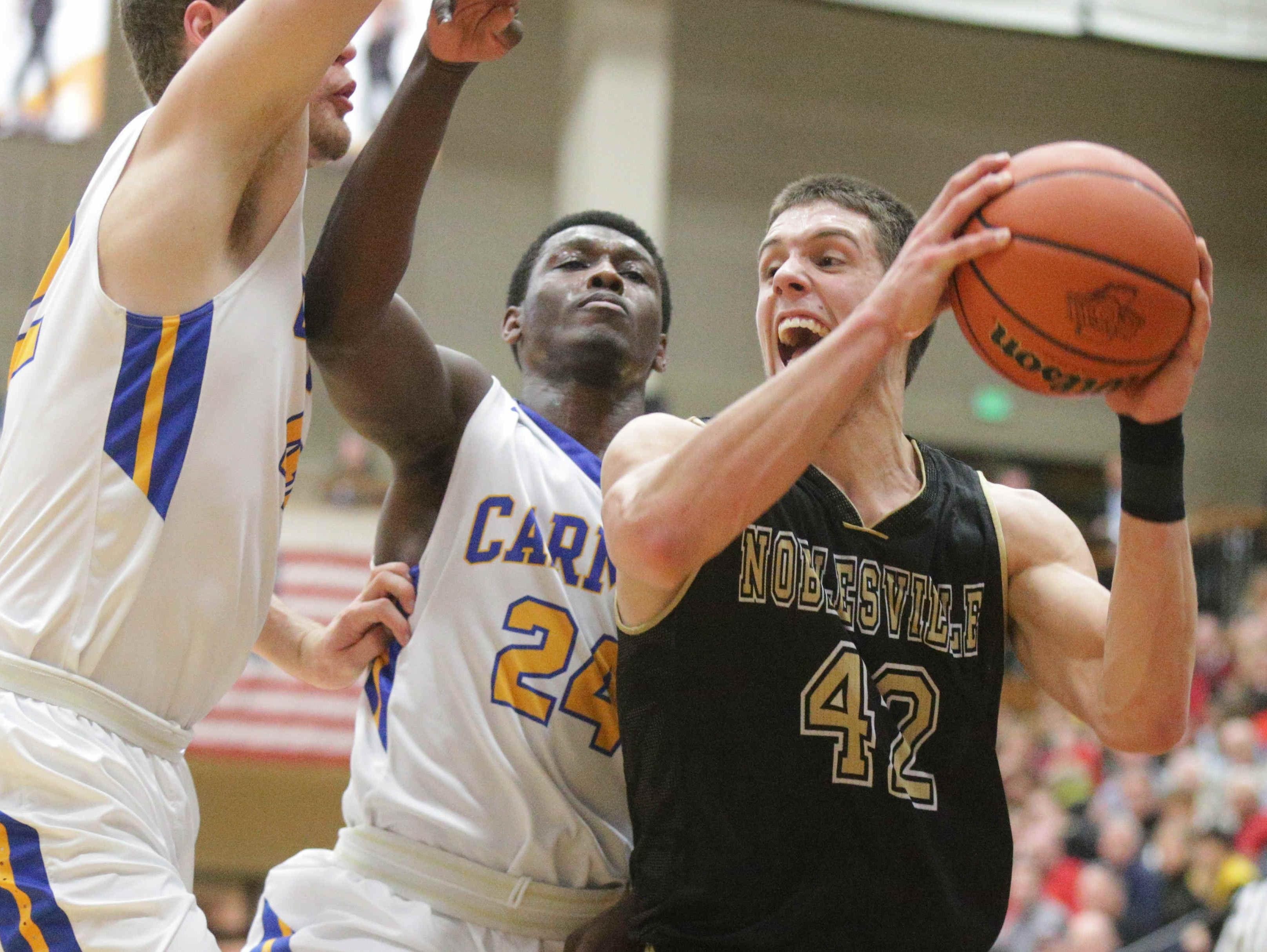 Noblesville's John Kiser (42) snatches a rebound from Carmel's Garrett Covington (24) and Trenton Richardson on March 2, 2016, in Indiana High School Athletic Association first-round sectional action at Noblesville.