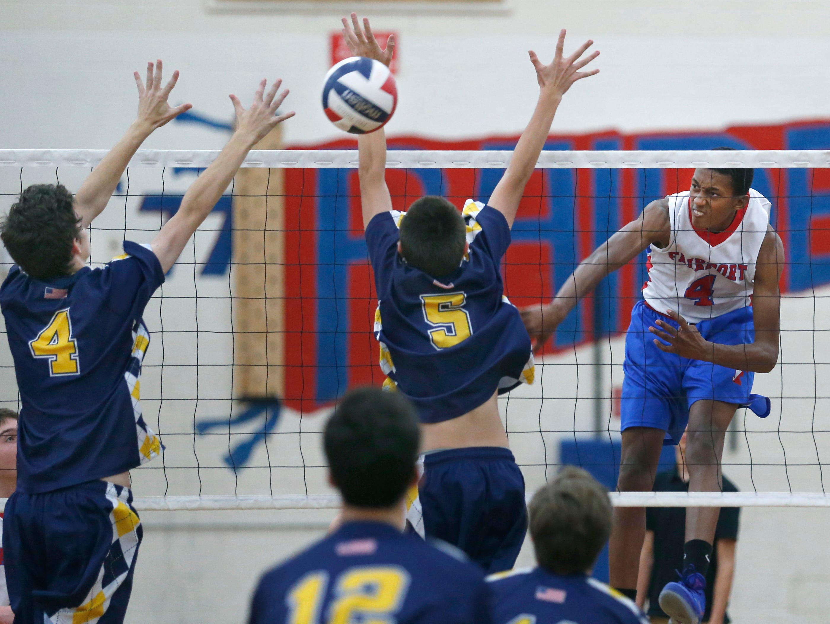 Fairport's Donovan Dey attacks against Victor's Hayden Hall and Cam Clark in the second set at Fairport High School.