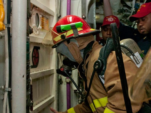 A sailor checks a door for heat before entering during