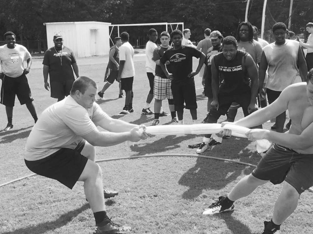 Lincoln Trojans offensive linemen Tom Moss (left) and Casey Warming square off in a tug-of-war battle during summer workouts last week, on a day dubbed “Competition Thursday.”