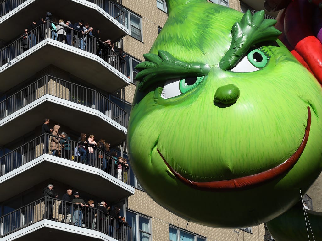 People watch the Grinch Balloon pass by during the annual Macy's Thanksgiving day parade.