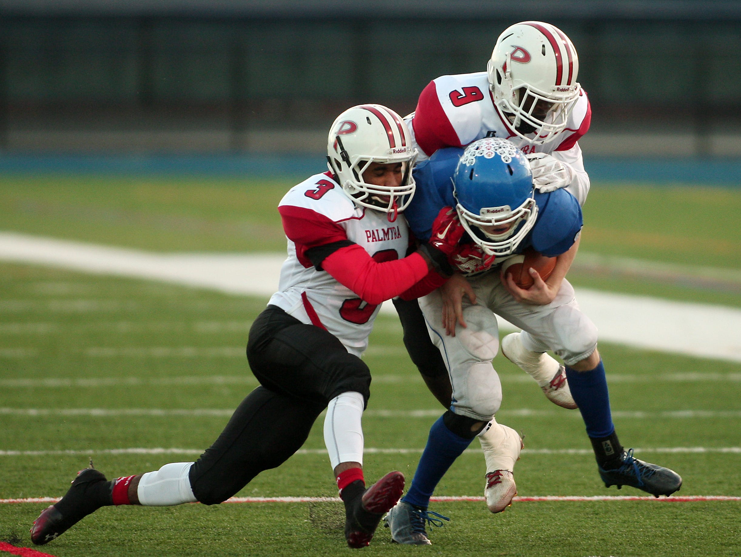 Shore Regional's Alex Johnson is taken down by Palmyra's Kameron Kennedy and Kelvin Harmon during their NJSIAA Central, Group 1 Championship game at Kean University Alumni Stadium. December 5, 2015, Union, NJ.