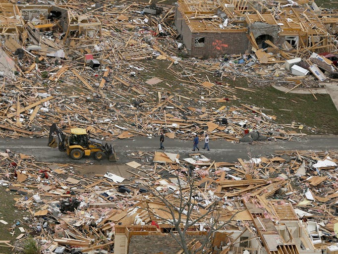 People walk between homes destroyed by a tornado on April 28 in Mayflower, Ark. At least 18 people were killed when a storm system ripped through several states on April 27.