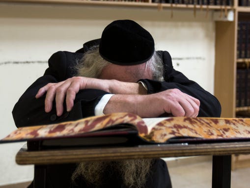 An elderly Jew is in deep prayer in the main hall of