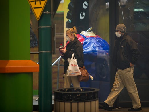 People wearing face masks walk down the Parkway in