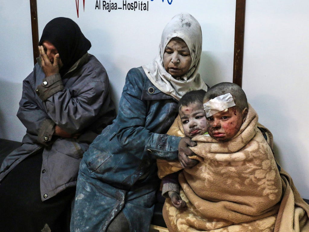 A Syrian woman sits with injured children at a hospital following a reported strike by government forces in the rebel-held distric of Barzah, Syria.