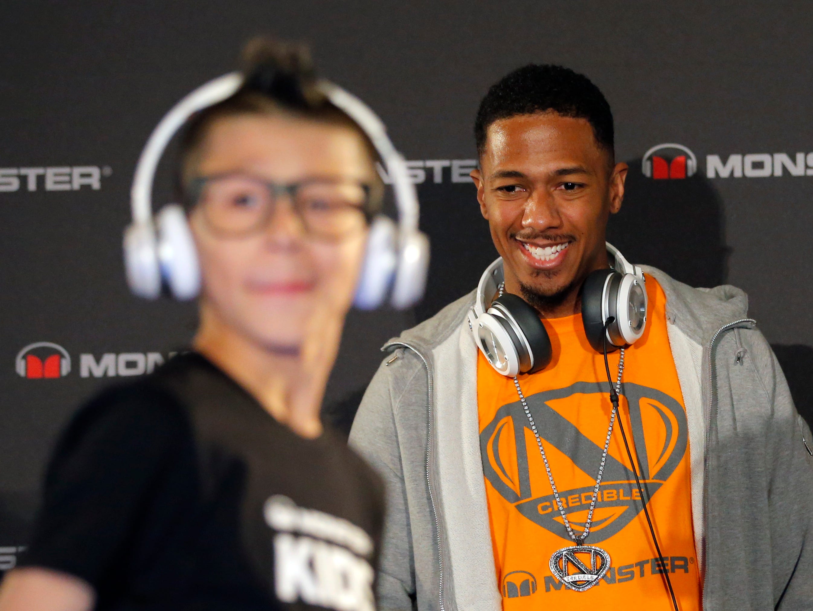 Recording artist Nick Cannon looks at a model wearing a new headphone by Monster during a new conference at the International Consumer Electronics Show in Las Vegas, Monday, Jan. 7, 2013.