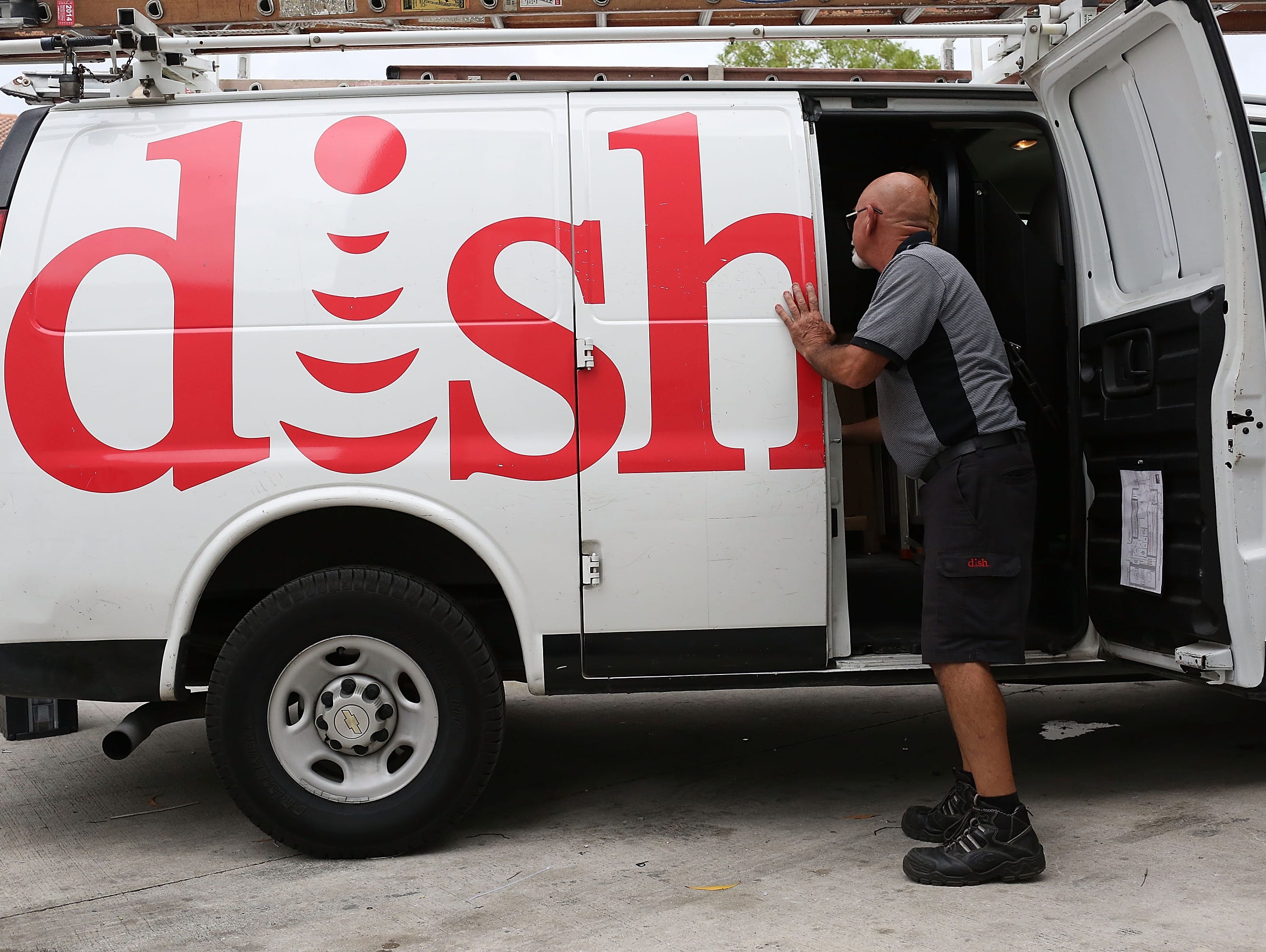 Alberto Rodriguez, a Dish Network technician works around one of the company trucks on June 4, 2015 in Miami, Florida.