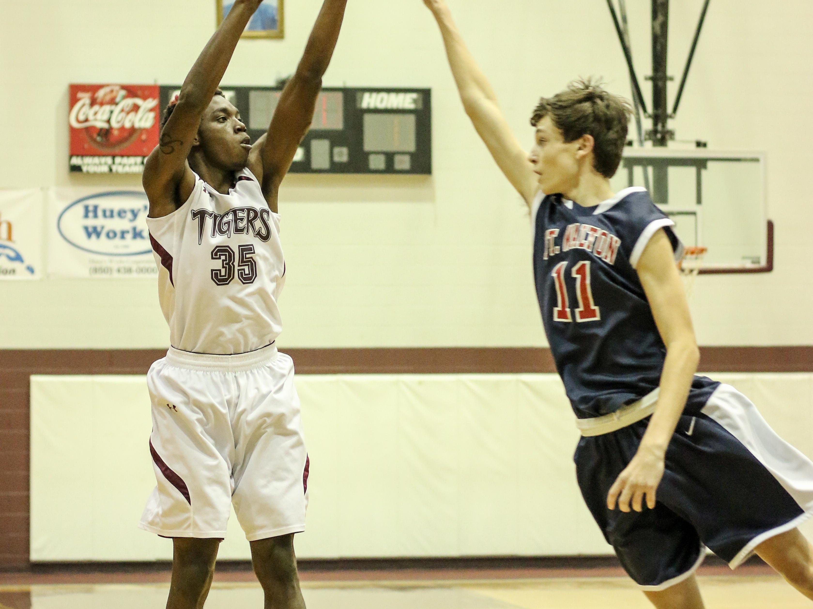 Pensacola High's Cardriques Baggage, left, gets a three point shot off as Fort Walton Beach High's Jack Lavin misses the block during the District 1-6A quarterfinal playoff game Thursday night at Pensacola High School.