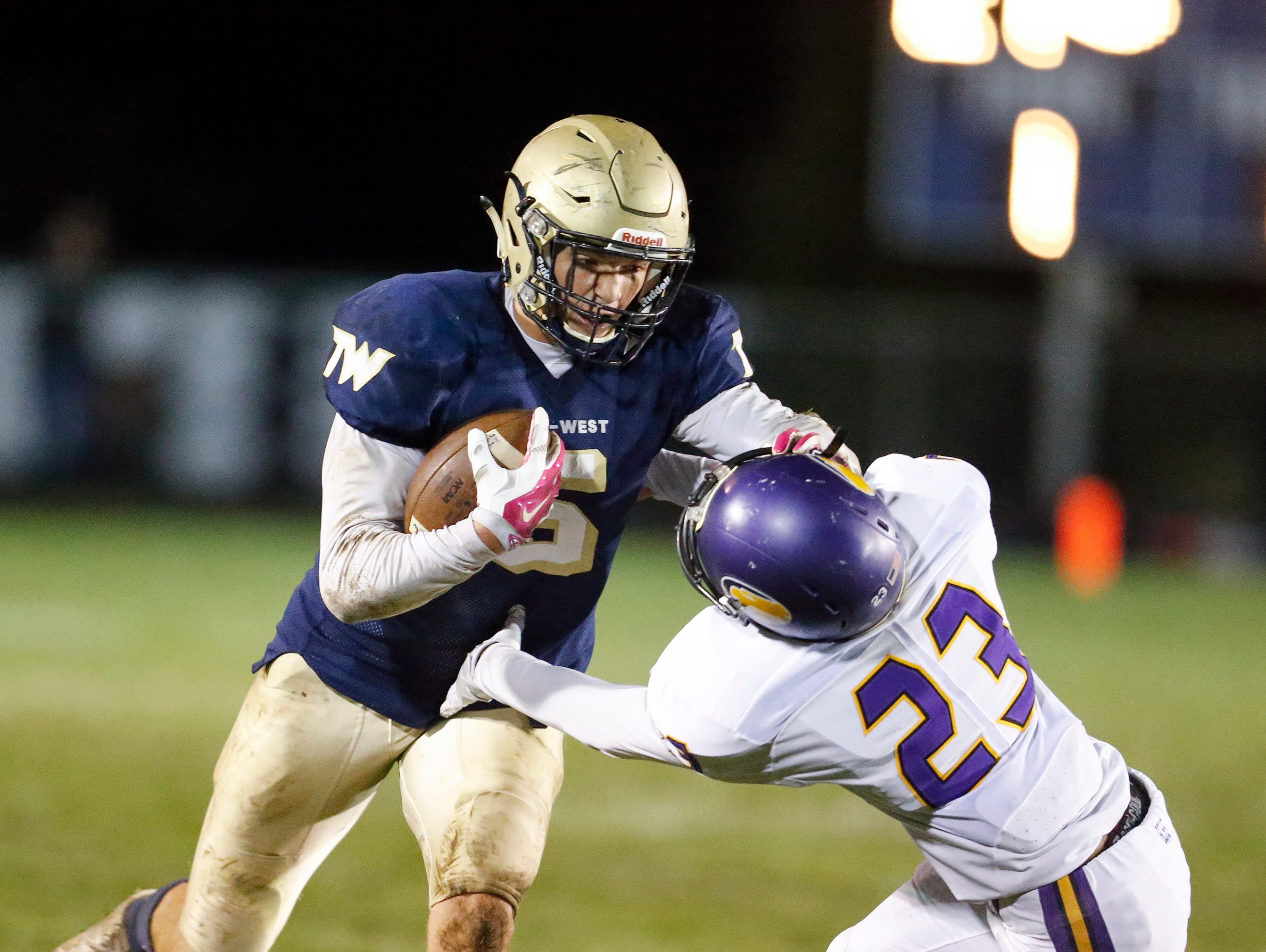 Tri-West's Peyton Hendershot (5) stiff arms Guerin Catholic's Shawn Balance (23) during their sectional game at Tri-West.