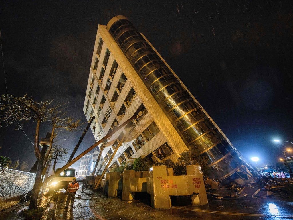 A rescue worker, bottom left, walks past beams used to prop up the Yun Tsui building as it leans to one side after an overnight earthquake in the Taiwanese city of Hualien on Feb. 7, 2018. Rescue workers pulled survivors and bodies from buildings til