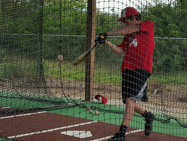 LaBelle Tyler Burton prepares for a game by hitting in the batting cage.