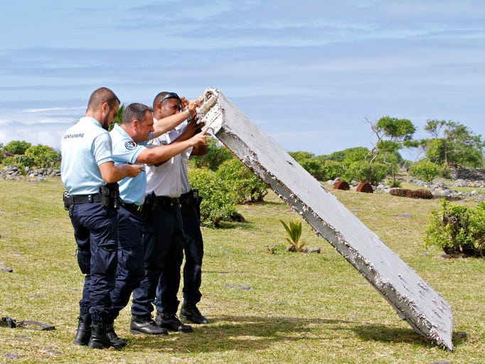 French police officers inspect a piece of debris from