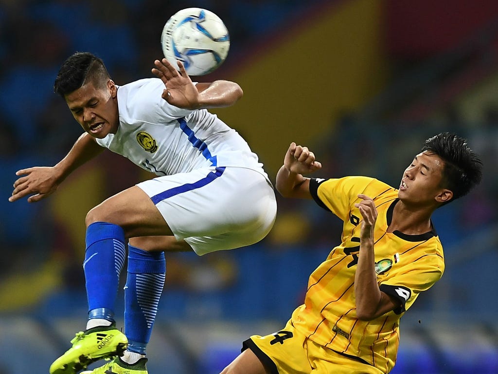 Jafri Firdaus Chew, left, of Malaysia fights for the ball with Haziq Kasyful Azim of Brunei during their men's football Group A match at the 29th Southeast Asian Games (SEA Games) at Shah Alam Stadium in Shah Alam, on the outskirts of Kuala Lumpur, M