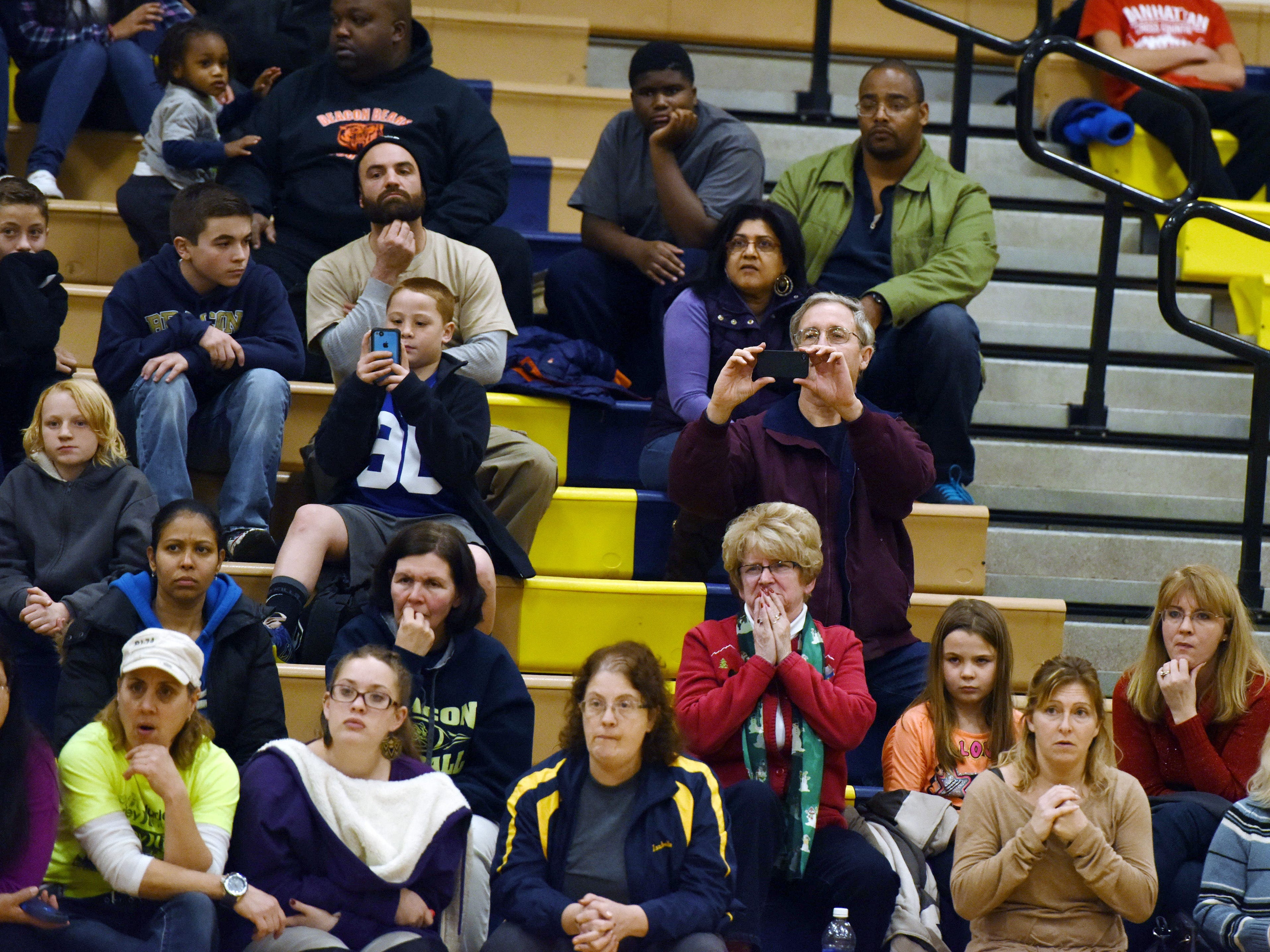 John Ollive, father of Beacon High School wrestler Liam Ollive, center right, watches and records his son wrestle in Beacon in December.