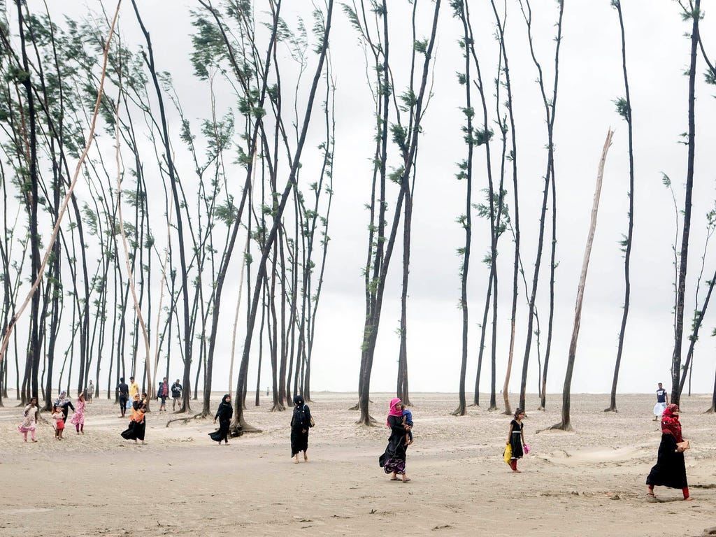 Bangladeshi people walk with their belongings towards a safer area near the coastal line at the Cox's Bazar in Bangladesh on May 30, 2017. At least five people are reported dead, 10 injured, and houses damaged after the cyclone Mora hit the southwest