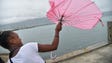 A girl tries to repair her umbrella that was broken