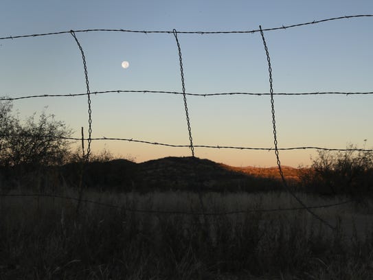A barbed wire fence stretches along the U.S.-Mexico