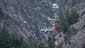 A rescue helicopter flies over debris of the Germanwings